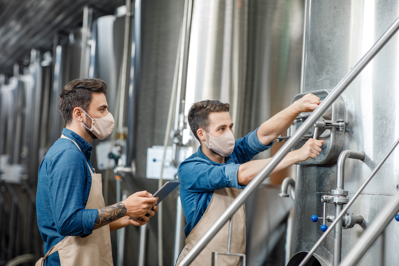 Beer production process. Two guys work with equipment